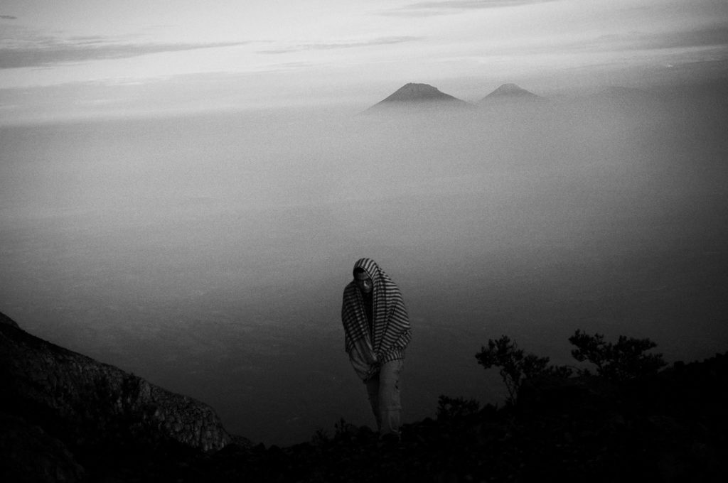 A mountaineer at the top of Mt. Merapi (2,968m) with Mt. Sindoro and Mt. Sumbing on the background. Mt. Merapi is one of the most active among 150 volcanoes in Indonesia with Merapi has erupted more than 80 times with the most recent one in 2006.