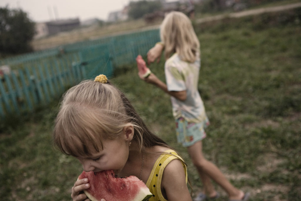 In short Russian summers, life takes place outside. Here, children eat watermelon in the afternoon in Tonshaevo village. Mari-El Republic. Russia. 2011.