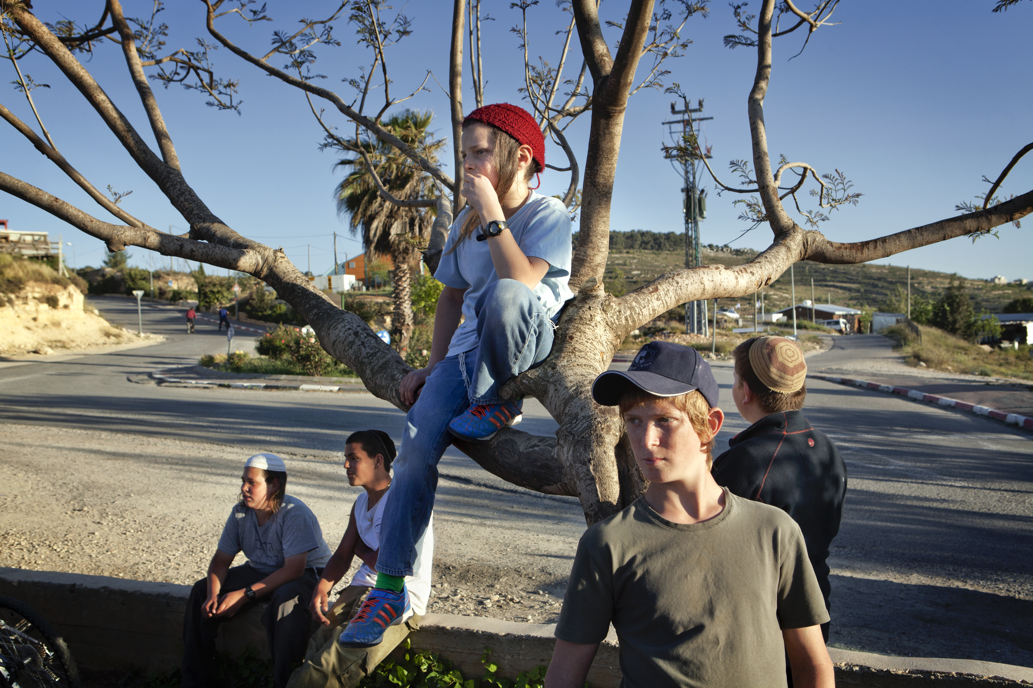 West Bank, 2013. Settlers. ### West Bank, 2013. Coloni. Settlement of Bat Ayin, West Bank, 2013.
Young boys watching the preparations for the
celebration of the State of Israel’s Independence
Day. Bat Ayin is a settlement located between Bethlehem and Hebron which was founded in 1989 by religious Zionists. The majority of its residents are practising Jews who support the Zionist efforts to build a Jewish state in the land of Israel.