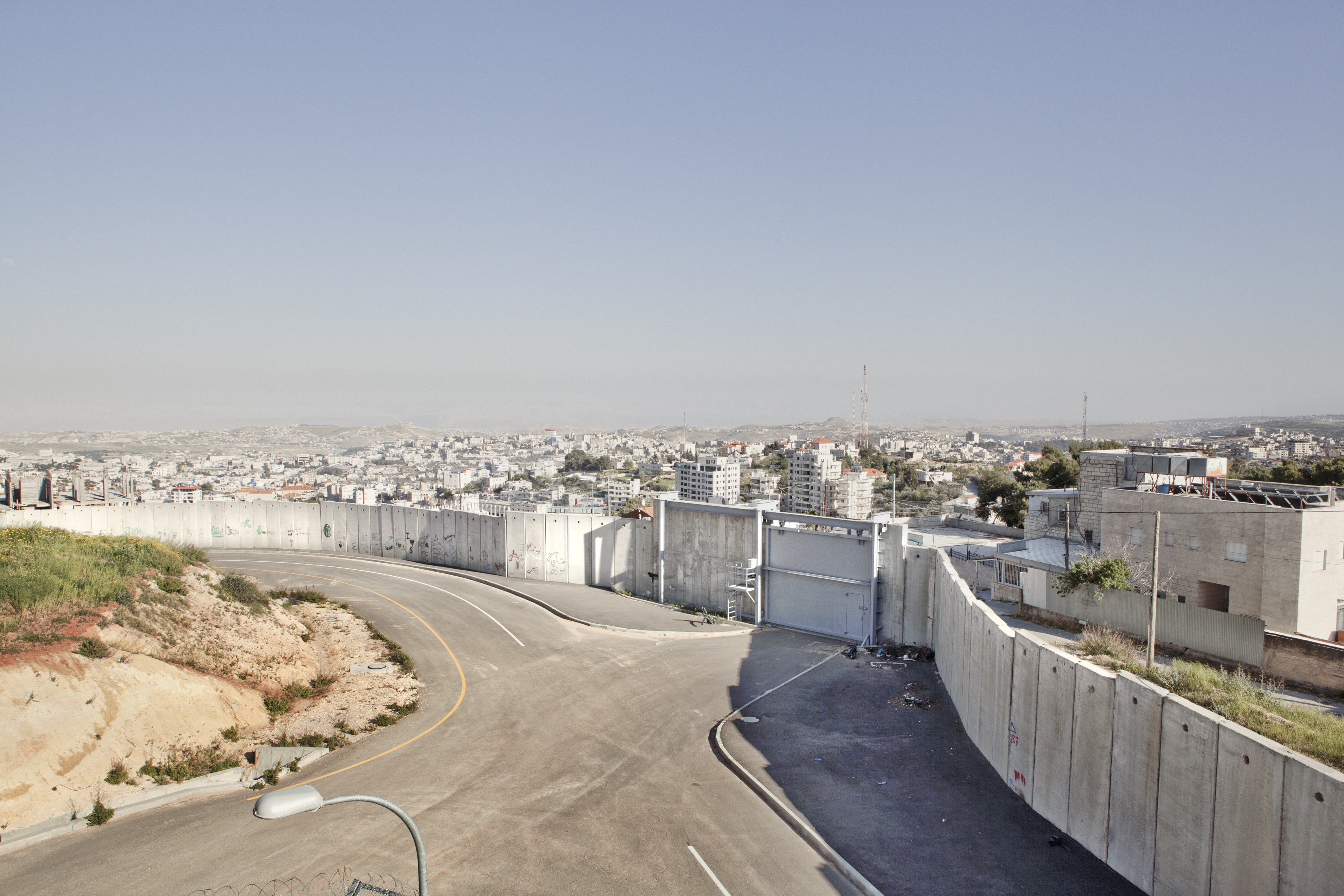 West Bank, 2013. Settlers. ### West Bank, 2013. Coloni. Settlement of Har Gilo, West Bank, 2013. Part of the separation wall that divides Israel and the West Bank, seen from the nearby settlement of Har Gilo. The wall, which is still under construction, is the subject of strong criticism, being well away from the 1949 Armistice Line and causing a real obstacle to freedom of movement for Palestinians. ### Colonia di Har Gilo, West Bank, 2013.
Una parte del muro di separazione tra Israele e Cisgiordania vista dal settlement di Har Gilo. Il muro, ancora in costruzione, è oggetto di forte contestazione essendo ben lontano dalla linea dell’armistizio del ’49 e provocando un
ostacolo concreto alla libertà di movimento dei palestinesi.