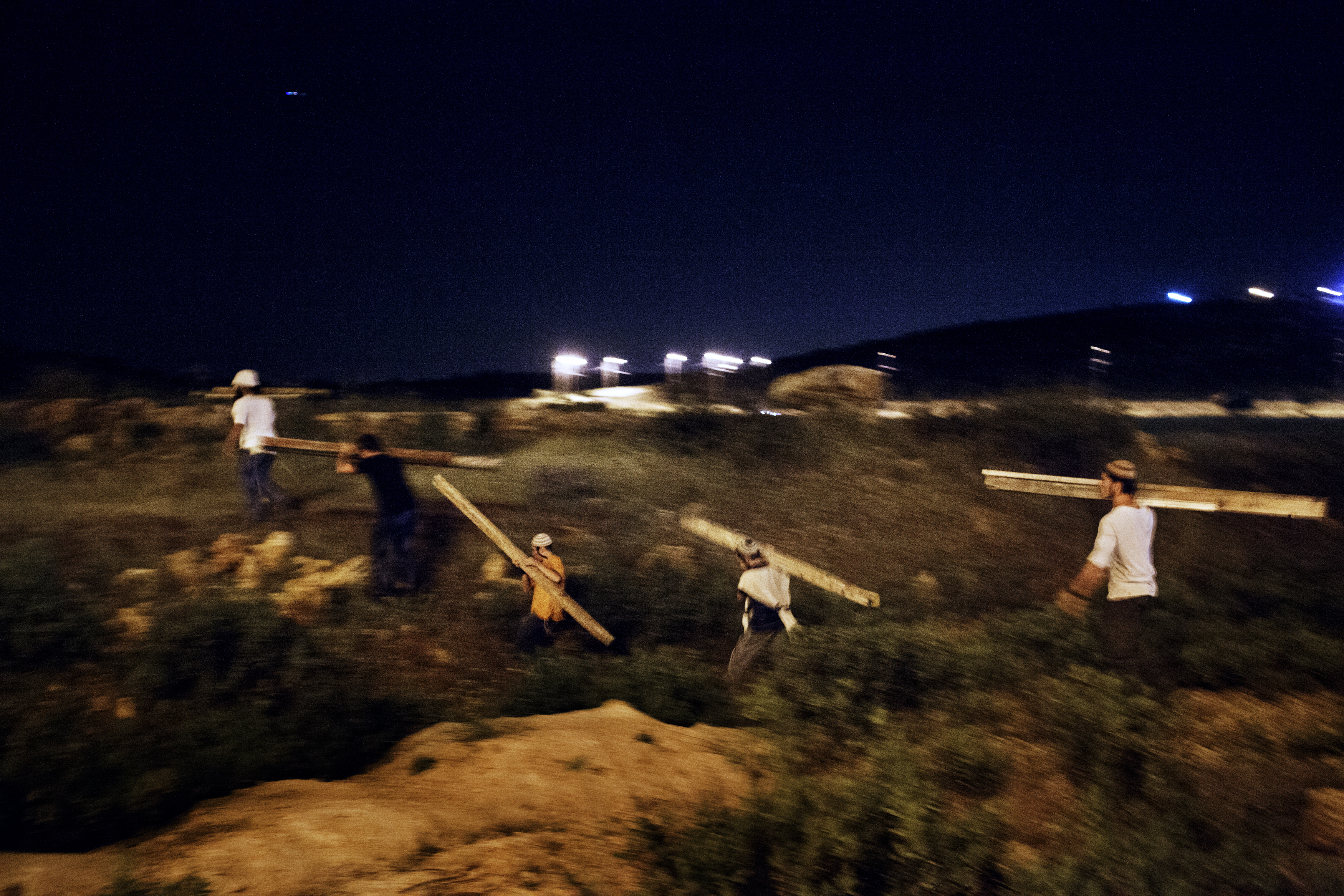 West Bank, 2013. Settlers. ### West Bank, 2013. Coloni. Tepuach Junction, south of Nablus, West Bank, 2013.
A group of settlers carrying planks of wood to erect
a tent as base for a new outpost on the site of the murder of Eviatar Borovsky, an Israeli settler stabbed to death the previous morning by a young Palestinian.