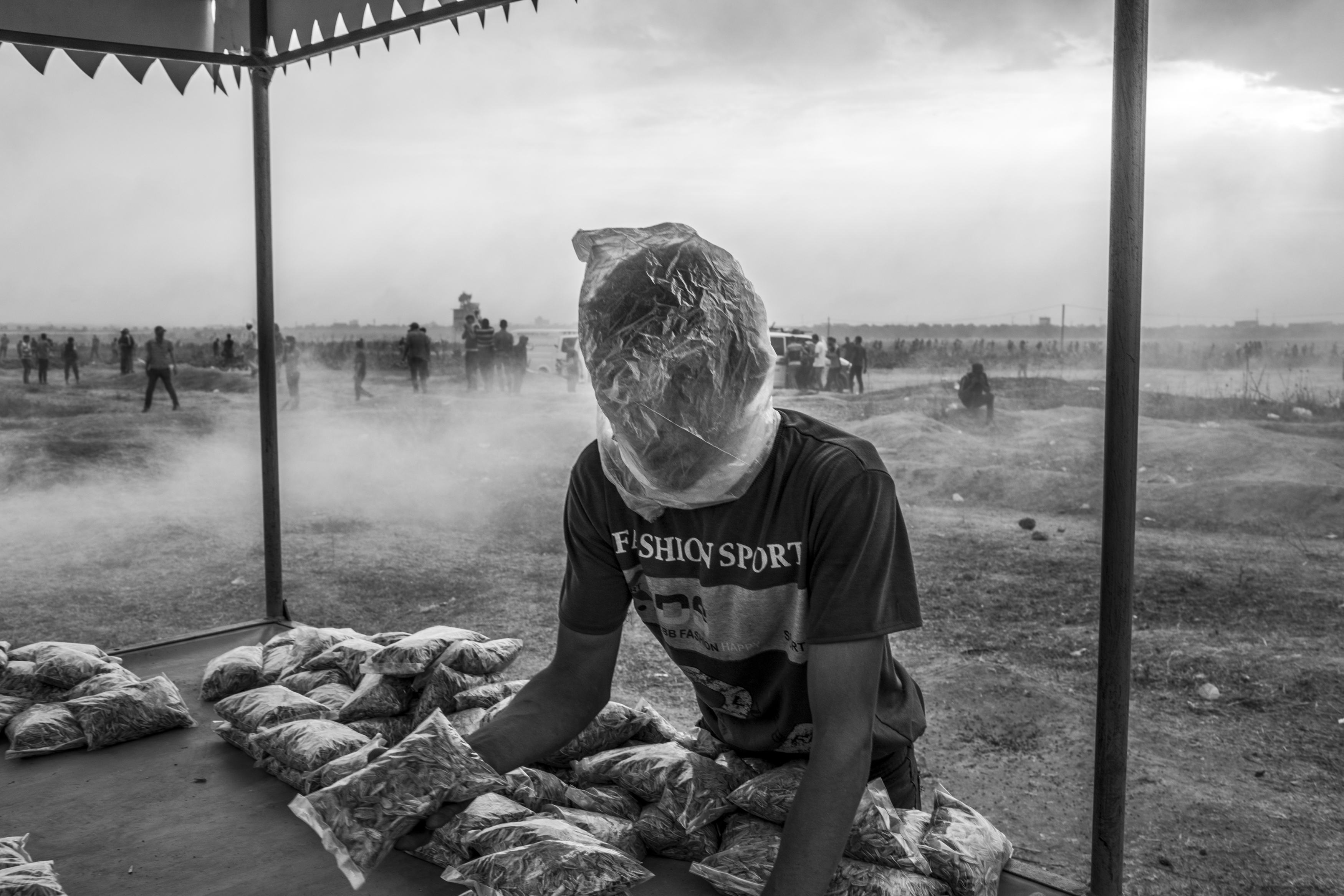 Gaza Strip, May 4, 2018. A Palestinian snack vendor uses a plastic bag to protect himself from the tear gas fired by Israeli forces during the sixth Friday of protest along the Israeli-Gaza border in Malaka area (eastern Gaza City).