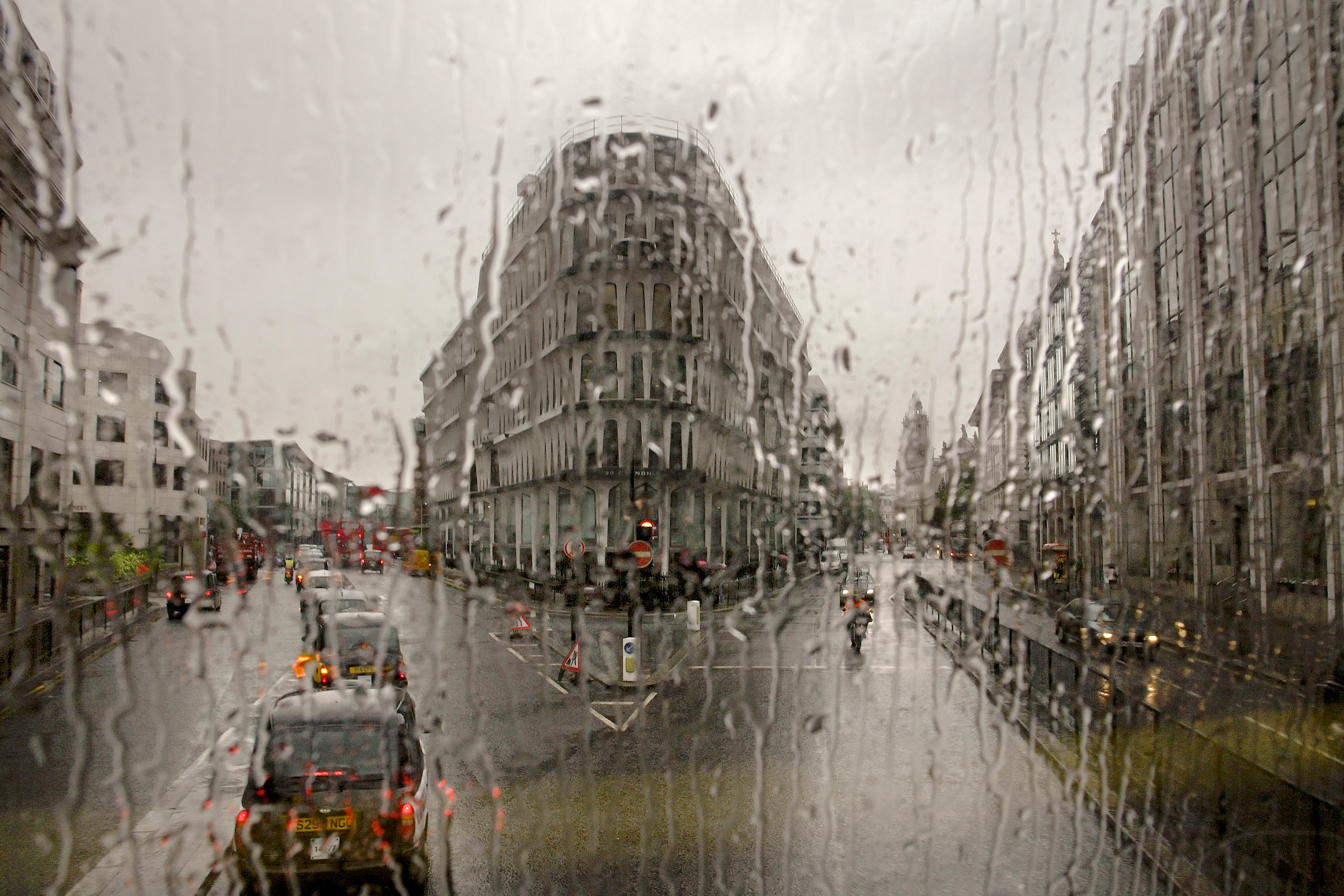 A view of a street junction in the City of London with a row of taxis is visible through a window of a bus covered in rain along the route of Bus 11 which runs from Liverpool street to Fulham Town Hall.[This image was photographed through the window of one of London's double decker busses and is part of 'Last Stop', a photo project now published as a book, which aims to document the city, its movements and migrations, its landscape and architecture, its diversity and energy.]