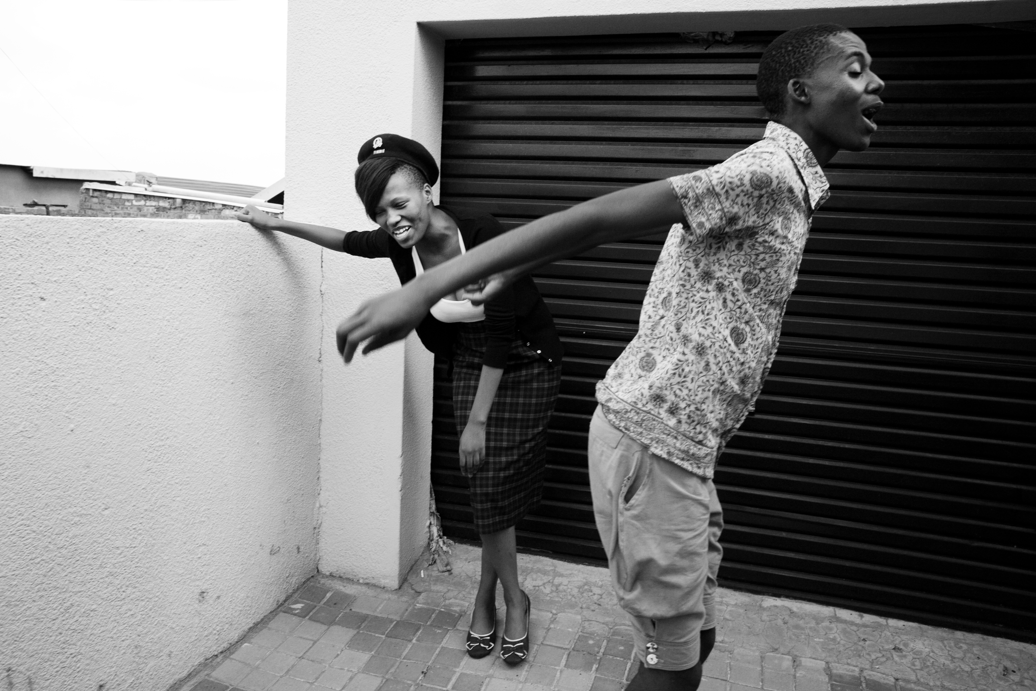 Smarteez member, Tumelo Nthekenyane, 21, right, jokes with a friend and model, left, who helps try on clothes of their new designs, outside other member Kepi's home in Soweto.Since the days of Apartheid to its inevitable end watched closely by the world, South Africans have fought hard for collective change. This collective spirit can be seen within the community in both the politics and the arts. Since the early post-Apartheid days, Kwaito—a musical genre and culture emerging out of the South African townships—has told stories beyond just the fashion and style of dance, but also to a life impoverished and the collective spirit of the young, sexual, and free looking towards change.Today, many middle class youth will argue whether Kwaito is dead or has just evolved. But one thing is certain: the new rising middle class youth of South Africa have begun to search for expression in more individual ways. Fighting a different fight from their parents, this generation is taking the opportunity to find their sense of self. One influential group emerging from Soweto’s streets calls themselves the Smarteez, after a popular, colorful candy. These young fashionistas are quickly joining the ranks of a growing middle class youth, inspiring a new generation to break from tradition and express individuality through fashion, music, and art. All original Smarteez members are from Soweto and either met growing up in the same Apartheid-styled neighborhoods or attending integrated suburban schools their parents viewed as gateways to new and better opportunities. As classmates at the University of Johannesburg’s fashion school, they bonded over a shared experience of being raised in these two distinct worlds. By sharing designs and crashing elite fashion parties, they created a milieu of risk-taking that evolved into a movement whose liberating ideas resonated with youth around the country.While South Africa still has the second highest murder rate in the world, one of th