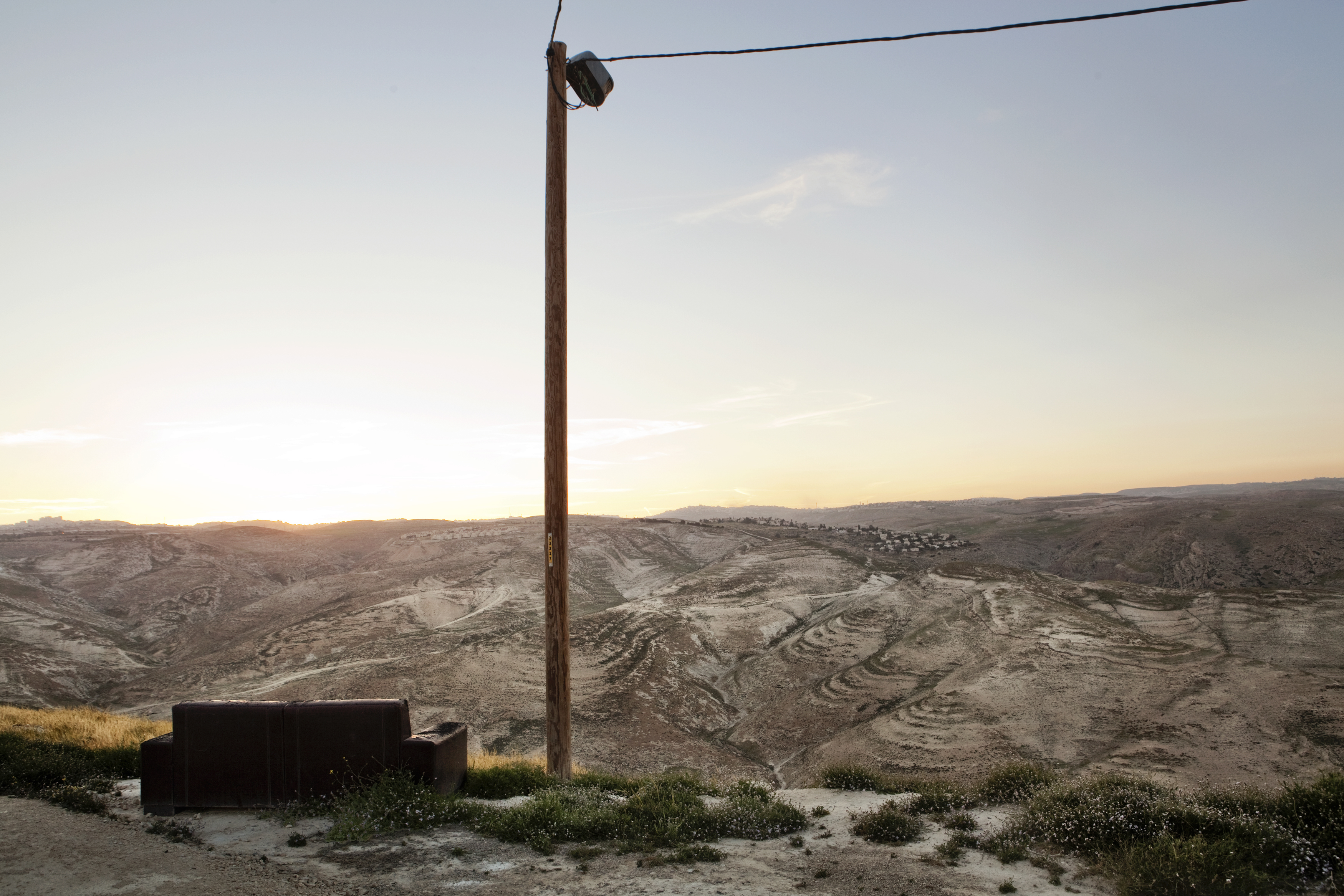 View from the Israeli outpost Alt 468, in the West Bank. The settlement of Almon is visible on the opposite hill, in the background Jerusalem. Most
of the Israeli settlements and outposts are located on top of
the hills and all are equipped with various security
features such as gates, electrified barriers, barbed
wire and sophisticated video surveillance systems.             ### Avamposto di Alt 468, West Bank, 2013.
Vista sulla valle e sulla colonia di Almon.
La maggior parte delle colonie e degli avamposti
sorge sulla sommità delle colline e sono tutti
dotati di diversi sistemi di sicurezza: cancelli,
barriere elettrificate, filo spinato e sofisticati
sistemi di video sorveglianza.