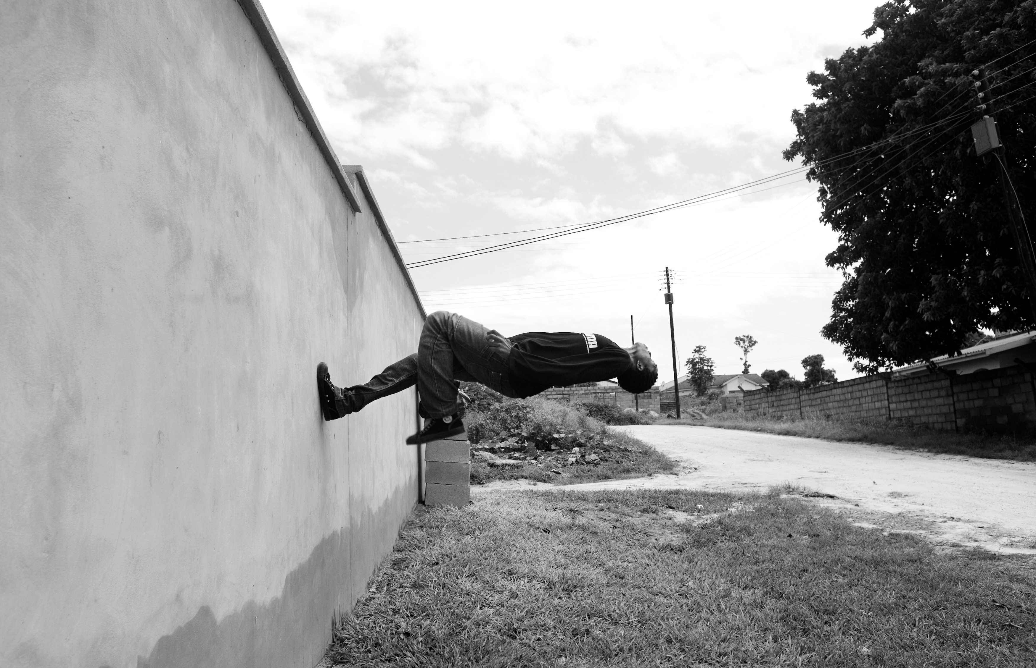 A teenager practices a flip off a wall in an urban neighborhood. He has joined his friends to create a hip hop dance crew in attempt to keep them off the streets and away from crime and drugs. Unemployment is forty-three percent in the country and leaves many teenagers leaving high school struggling to find a job.