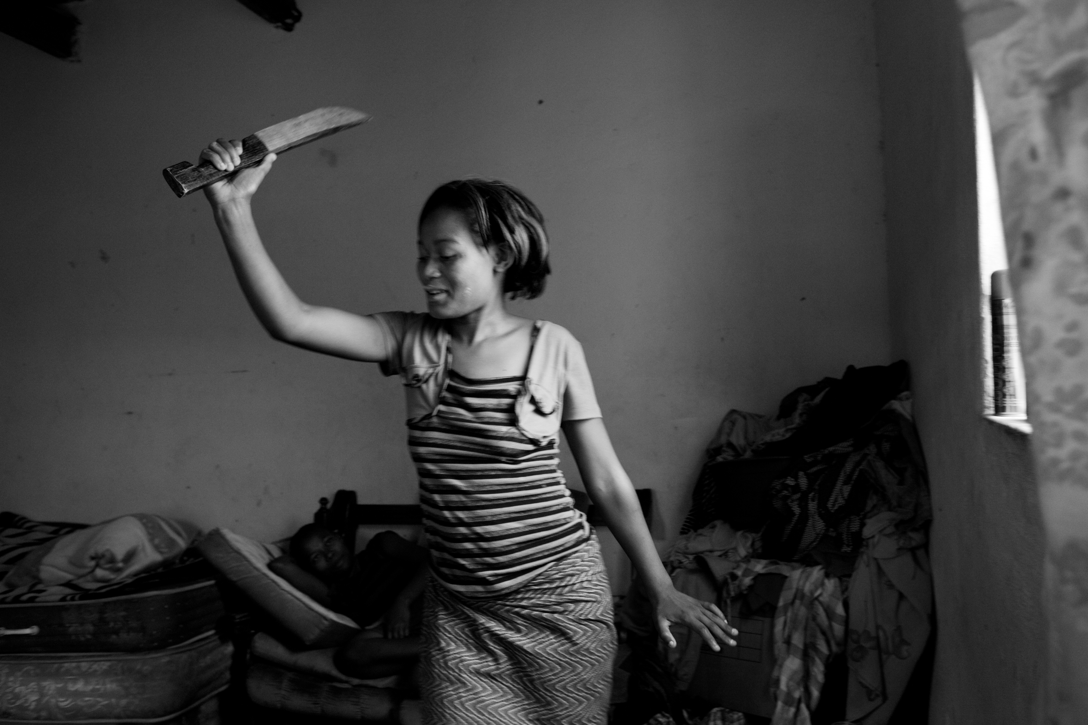 An HIV-positive woman, 20, dances in her room while visiting with friends. Since her young son died in September due to AIDS she has been depressed and drinking. She is scared to begin treatment due to stigma and fear.