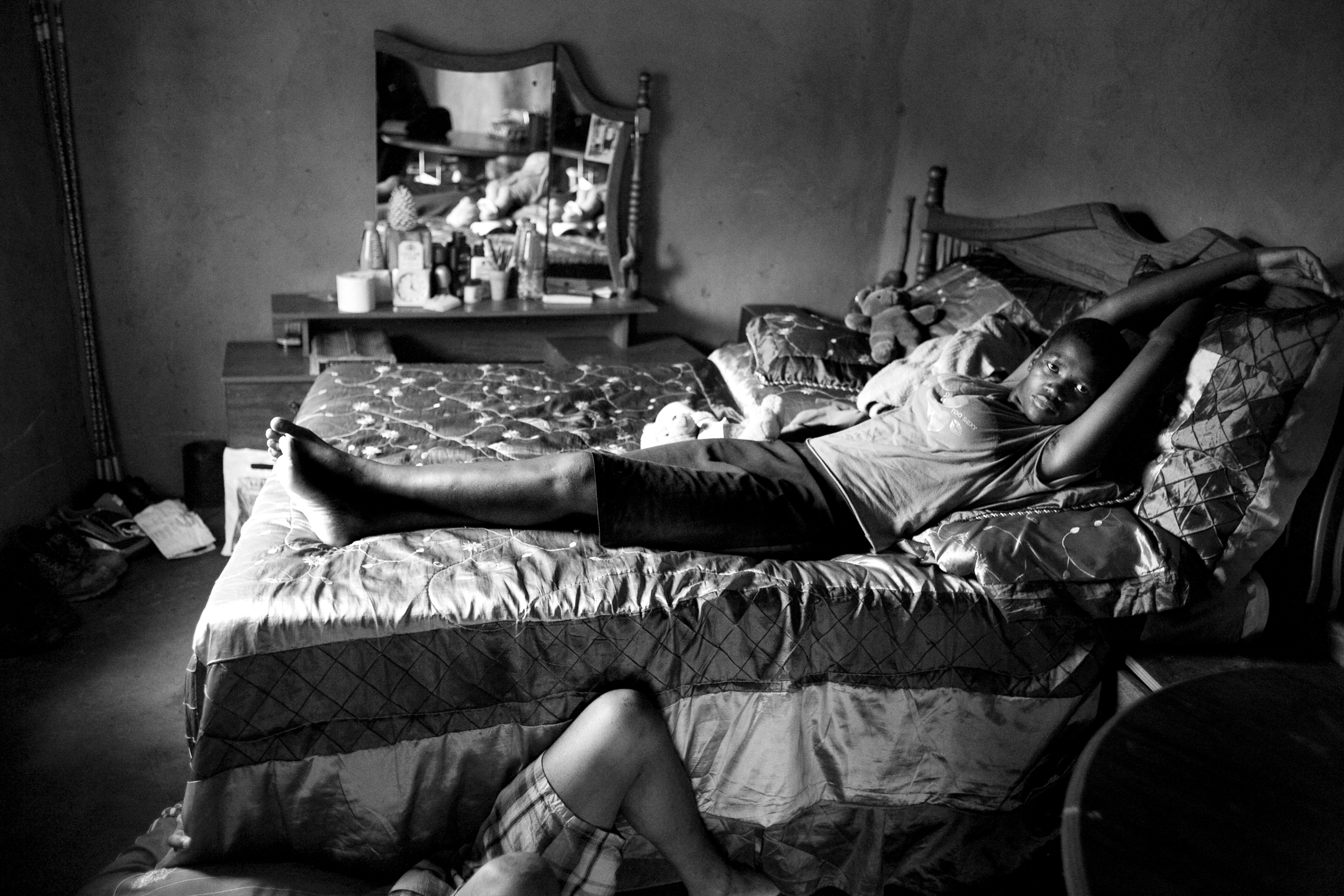 A young couple, both in their 20s, relax in their one bedroom home on a hot summer day. Many young couples live together before marriage if they cannot afford the lobola to marry.