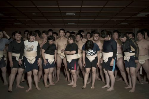 Sumo Training Hall, Asahi University, Japan.  Mambersof the Asahi University women sumo team prepare to pose for a group portrait with their male team members by the dohyo, or sumo ring, right after training. The team, both males ad females, practice most weekdays for at least two hours.
